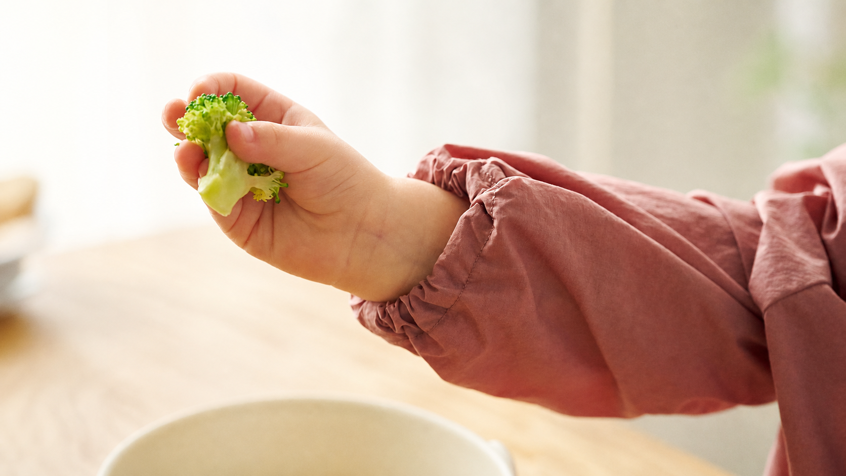 ブロッコリーを手に取り、食材の感触を確かめる子ども