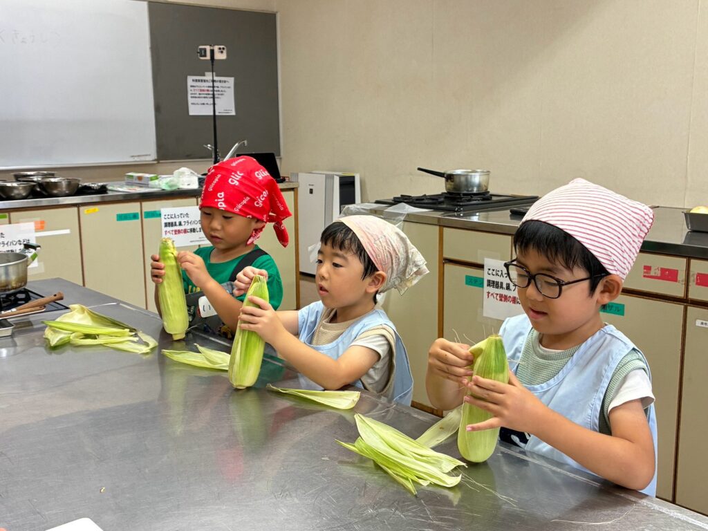 とうもろこしの皮とひげを自分の手で取り除く子どもたち