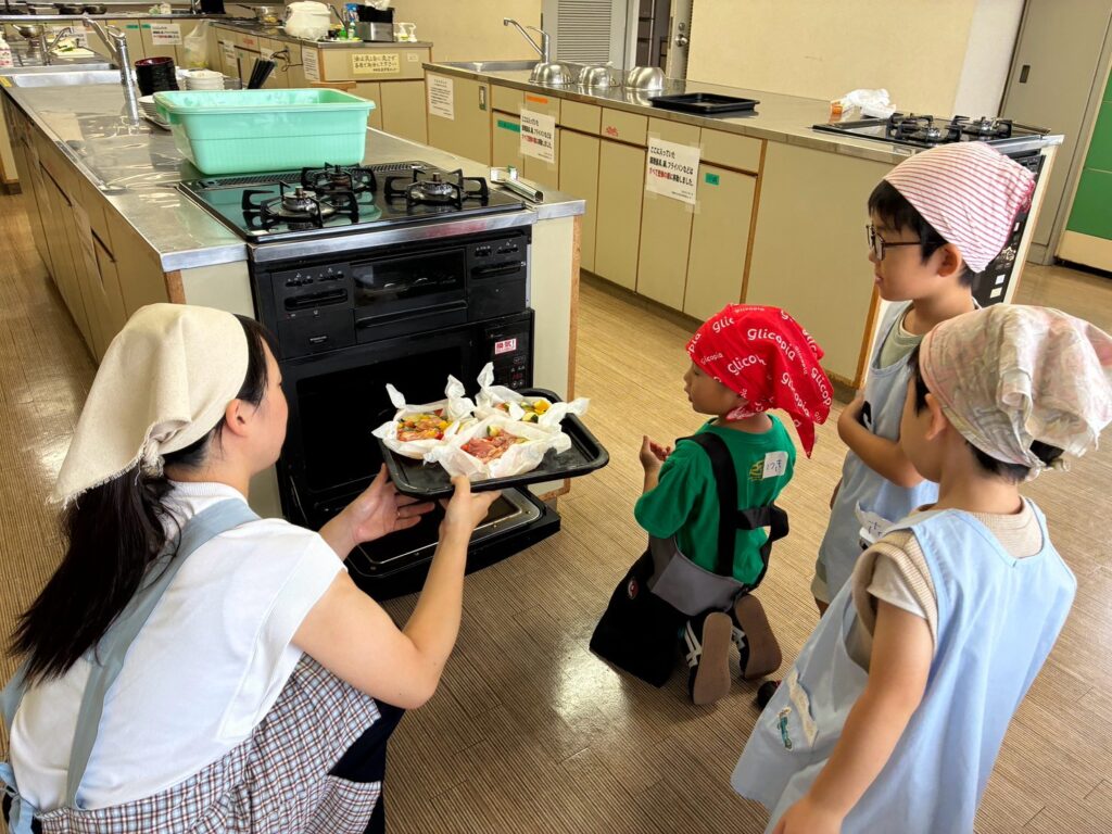 シートの上で夏野菜と肉を混ぜ、包み焼きの準備をする子どもたち