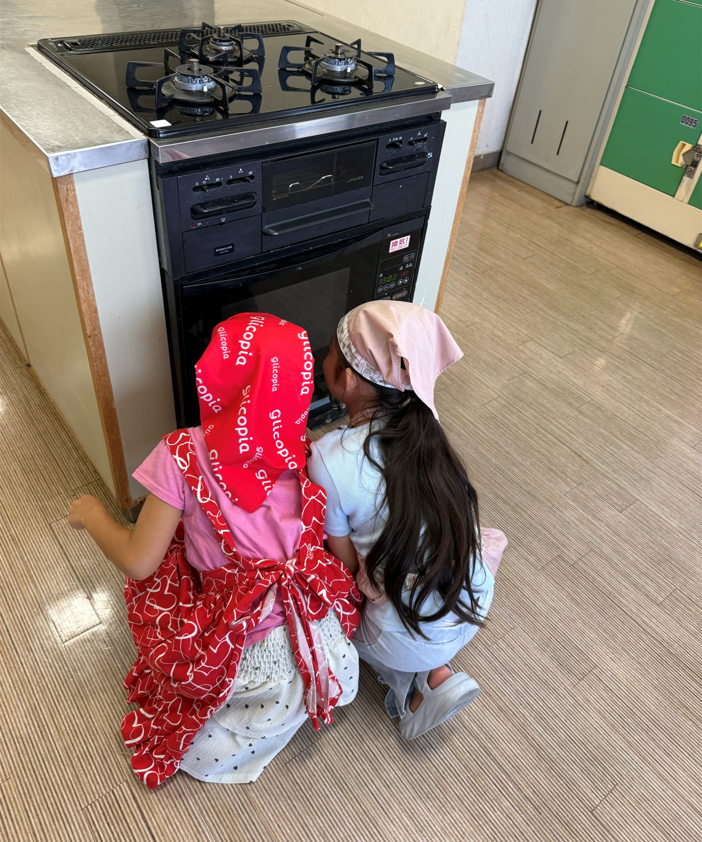 オーブンの前で焼き上がりを観察する子どもたち