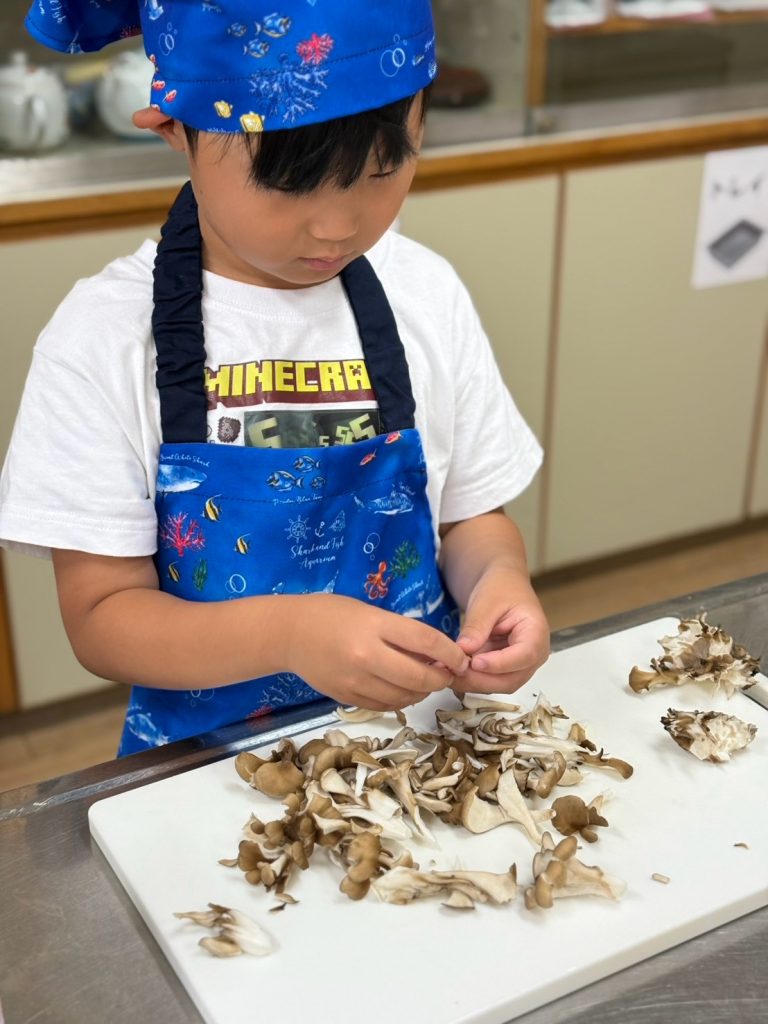 きのこを一本ずつ手でほぐす男の子
