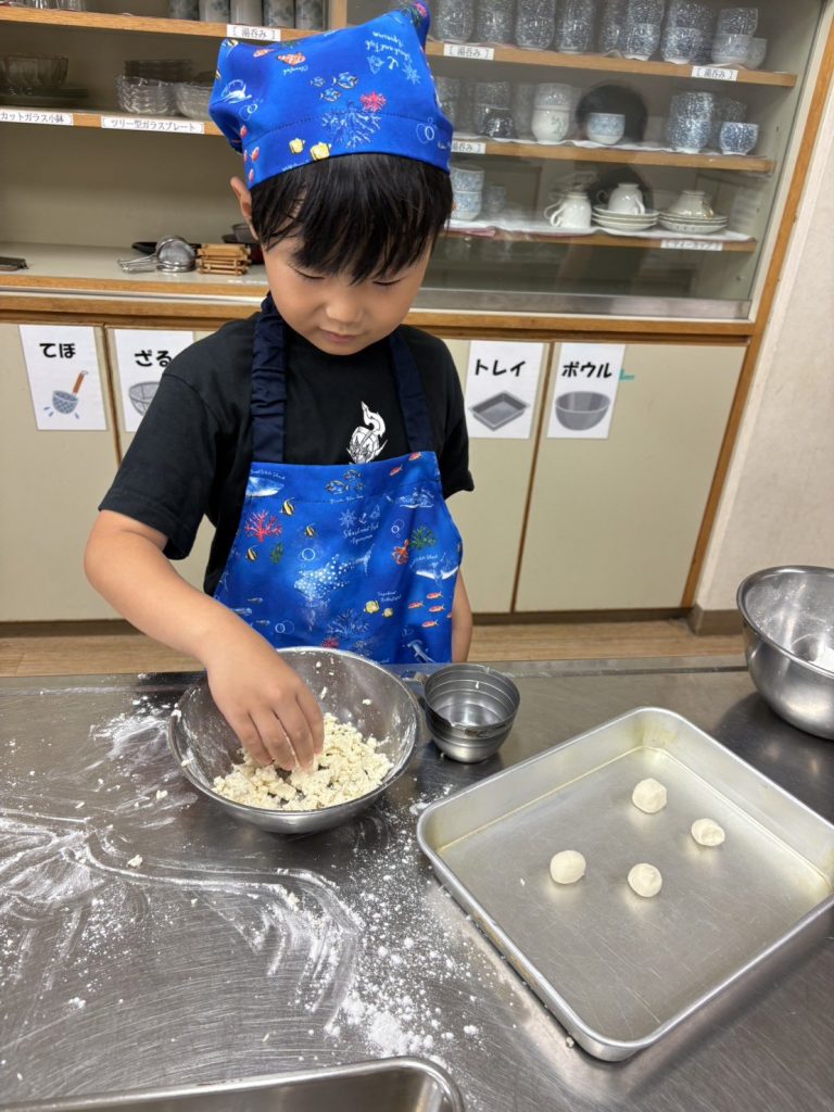 バットの前で団子を丸める男の子